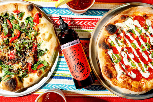 Two pizzas with a bottle of Sungrano Red Chile Oil