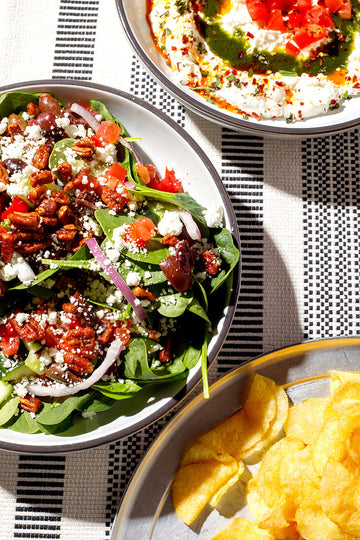 Spinach salad and chips on a striped tablecloth
